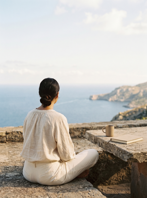Find Your Path — a calm woman in cream linen resting on a sunlit terrace overlooking the sea